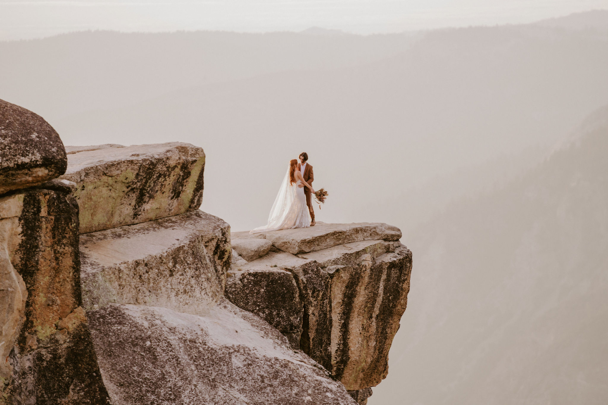 couple stands at taft point in yosemite after eloping