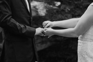 black and white of couple putting on rings