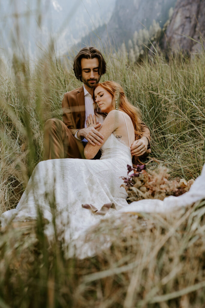 couple eloping at El Capitan Meadow laying in grass in Yosemite