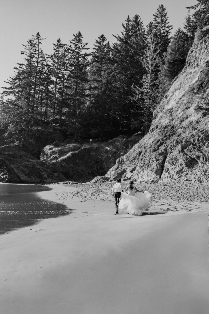 black and white of eloping couple running on the beach