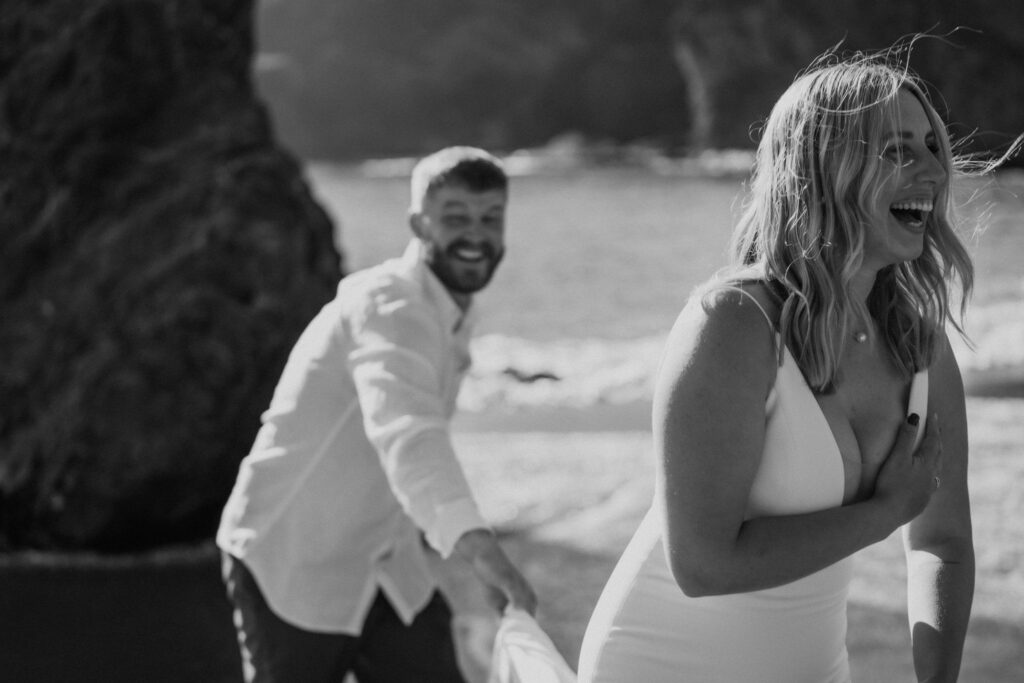 black and white of eloping couple playing on the Oregon beach