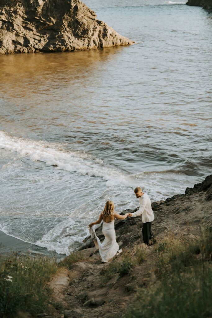 adventure elopement couple climbing to picturesque spot on the beach during oregon coast sunset elopement