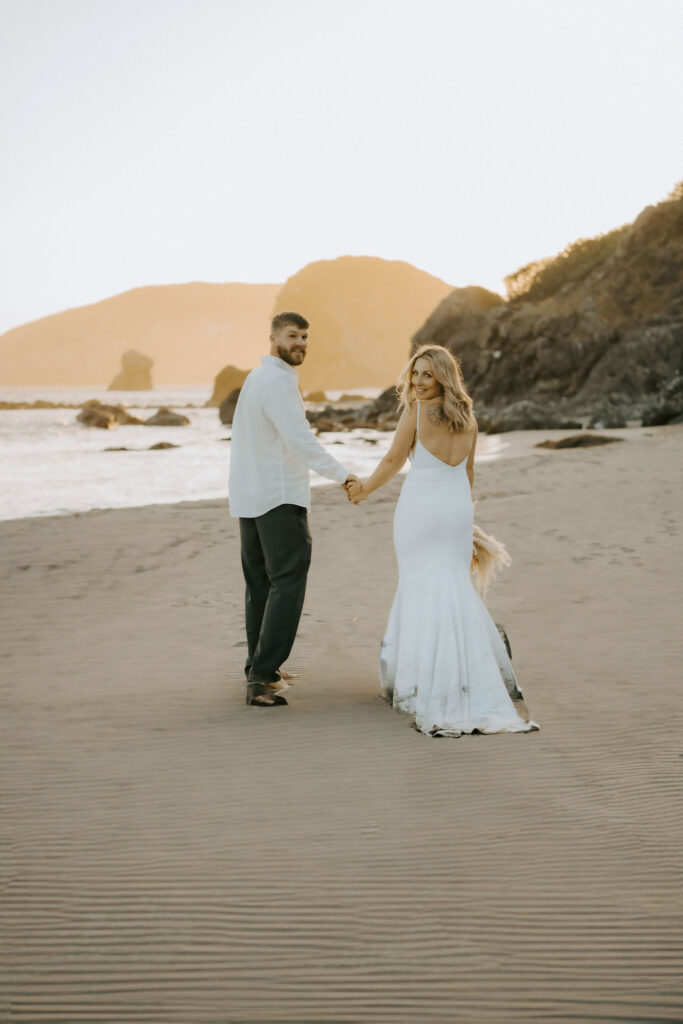 bride and groom walking towards the sunset on the beach during Oregon coast sunset elopement