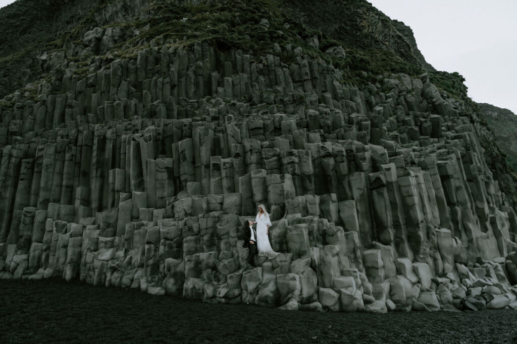 eloping couple on the rocks at Reynisfjara black sand beach in iceland