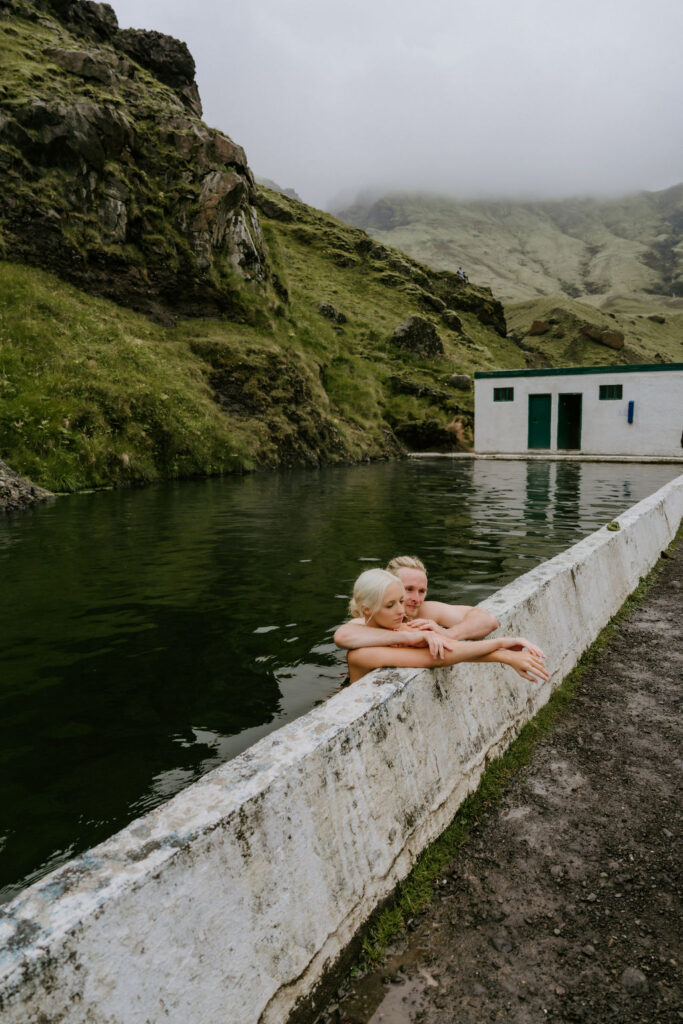 eloping couple enjoying a dip in Seljavallalaug hot spring in iceland