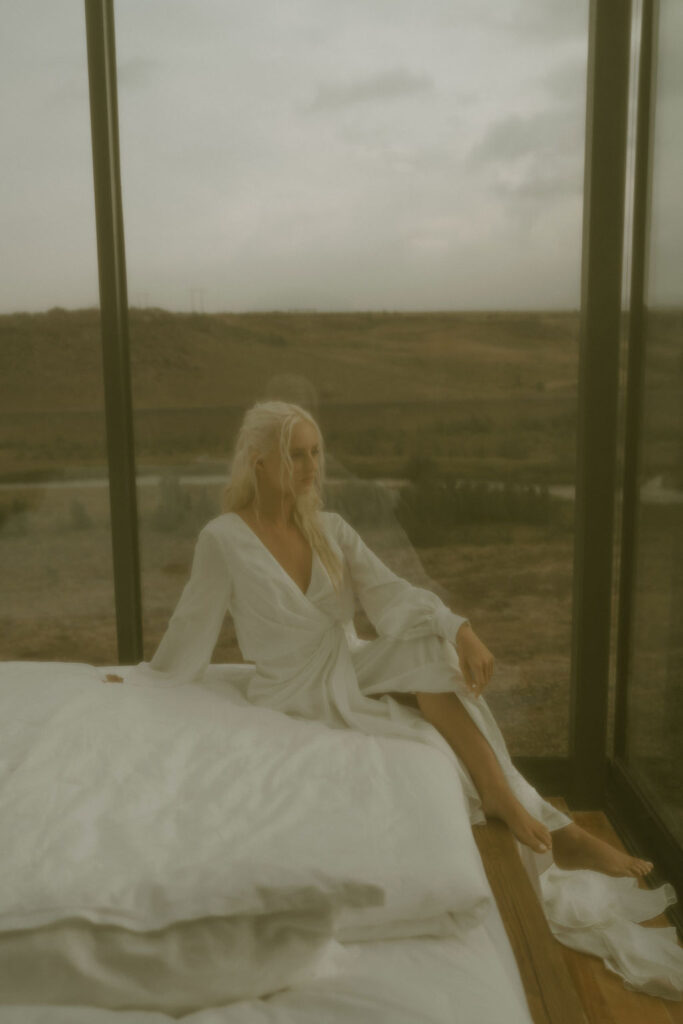 filmy image of bride on bed in panorama glass lodge in iceland