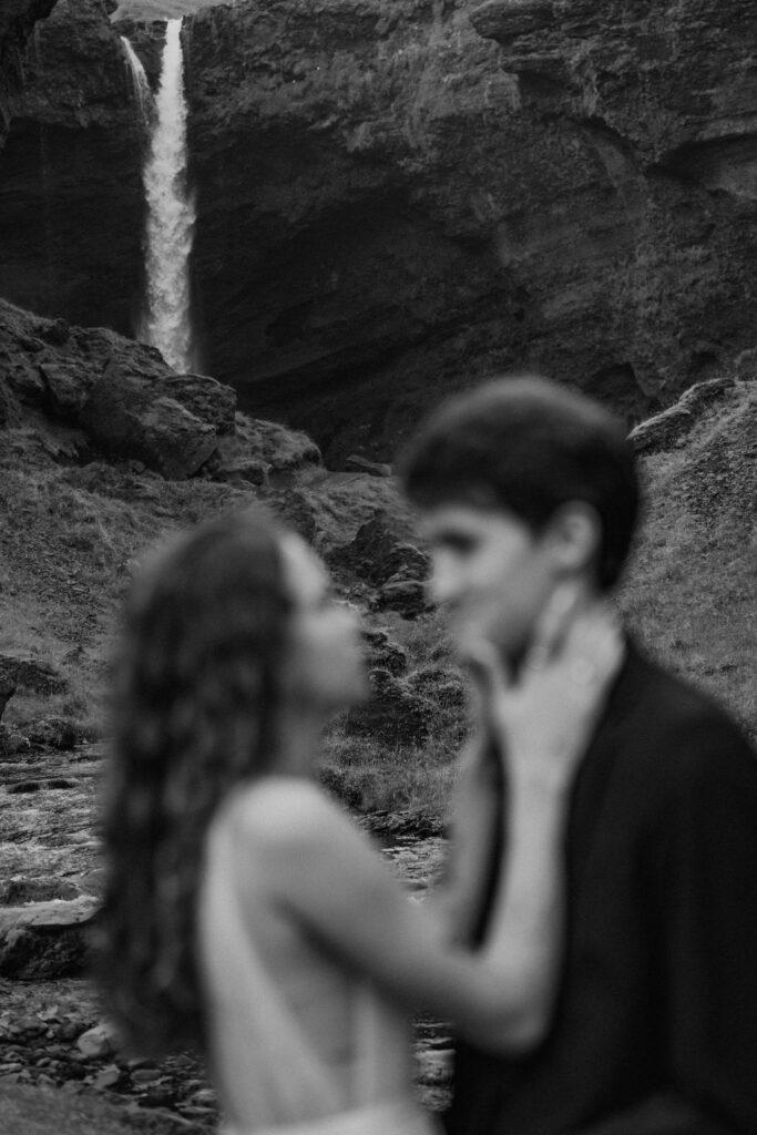 black and white detail of bride and groom in front of waterfall in iceland