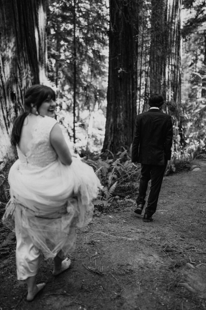 black and white of bride and groom walking in the redwood forest on california adventure elopement