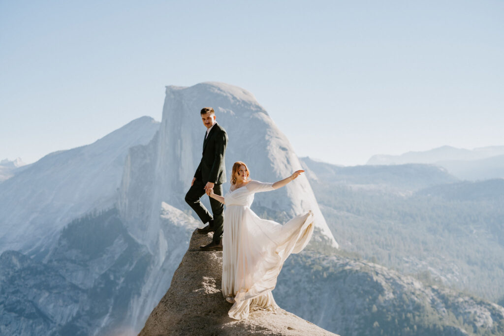 Bride throwing dress in the wind posing at Glacier Point