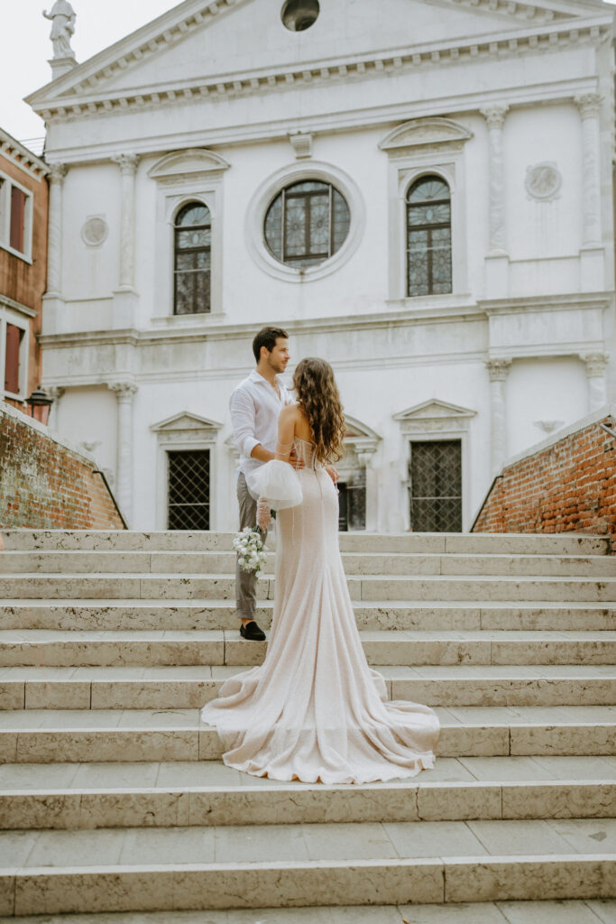 venice elopement couple on some steps with a historic building in the background
