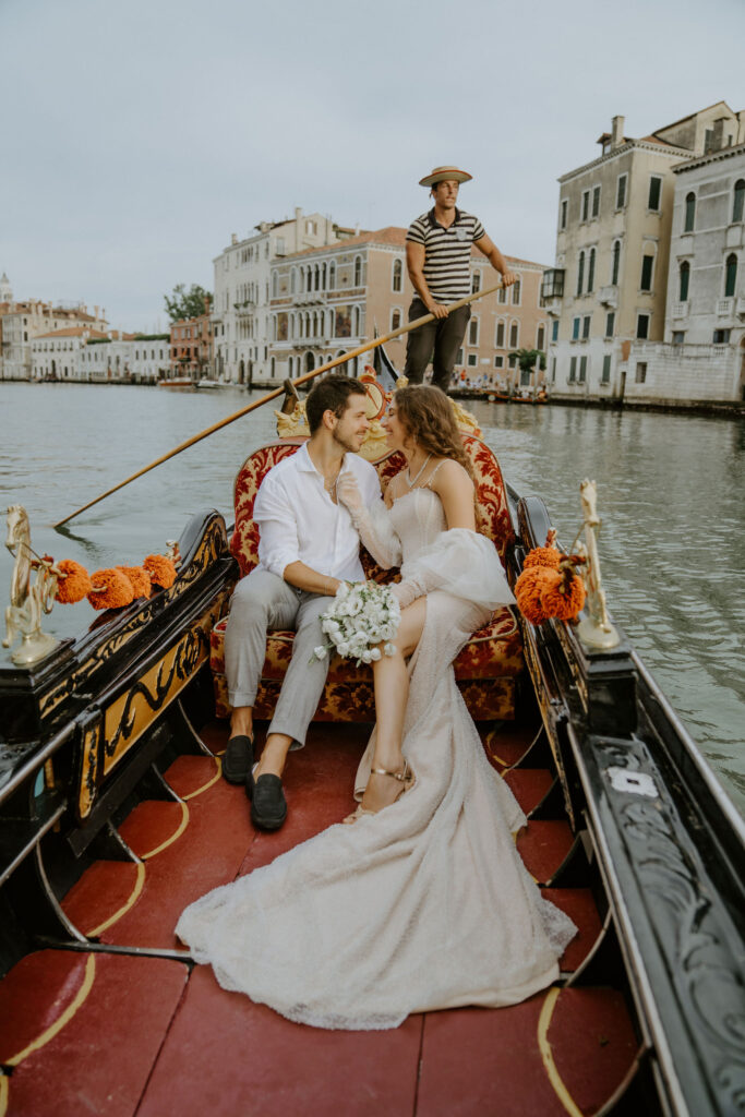 bride and groom sitting in a gondola, going down the canal during their venice elopement day