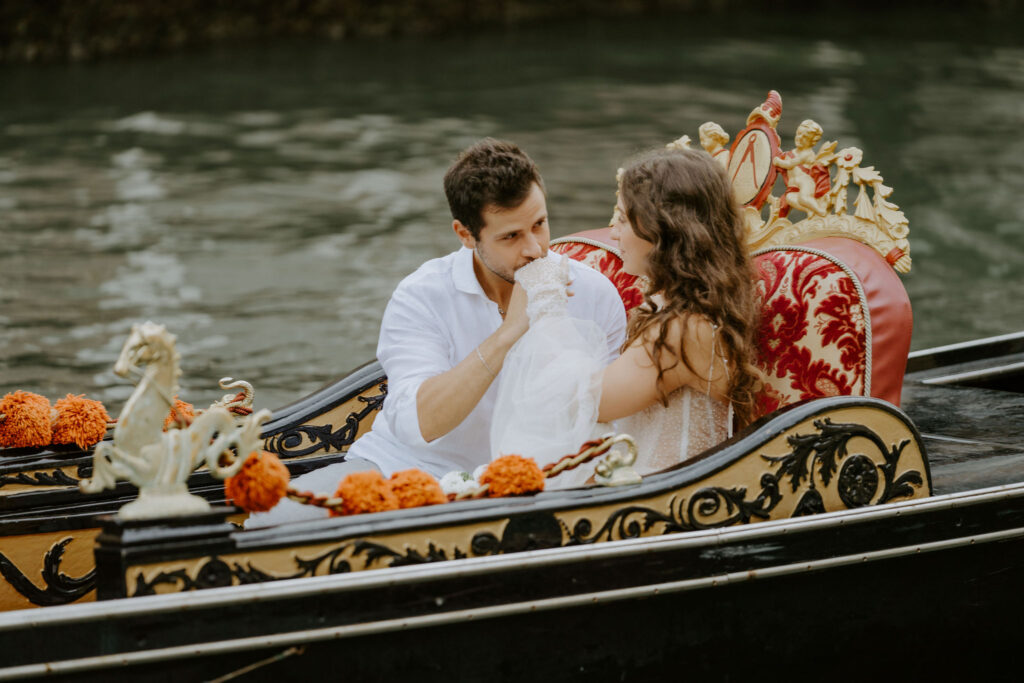 bride and groom sitting in a gondola, going down the canal during their venice elopement day