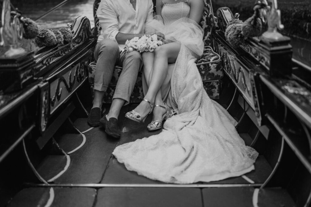 bride and groom sitting in a gondola, going down the canal during their venice elopement day