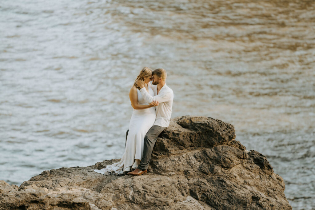 bride and groom sitting on a cliff during their southern california elopement