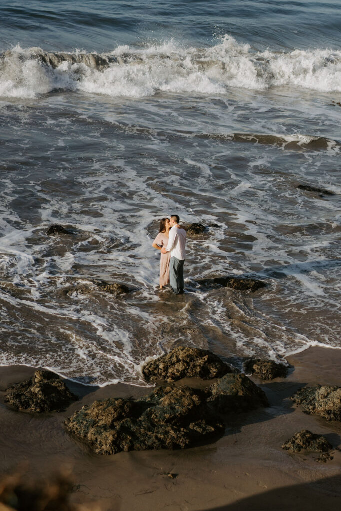 adventurous bride and groom standing in the ocean at el matador beach