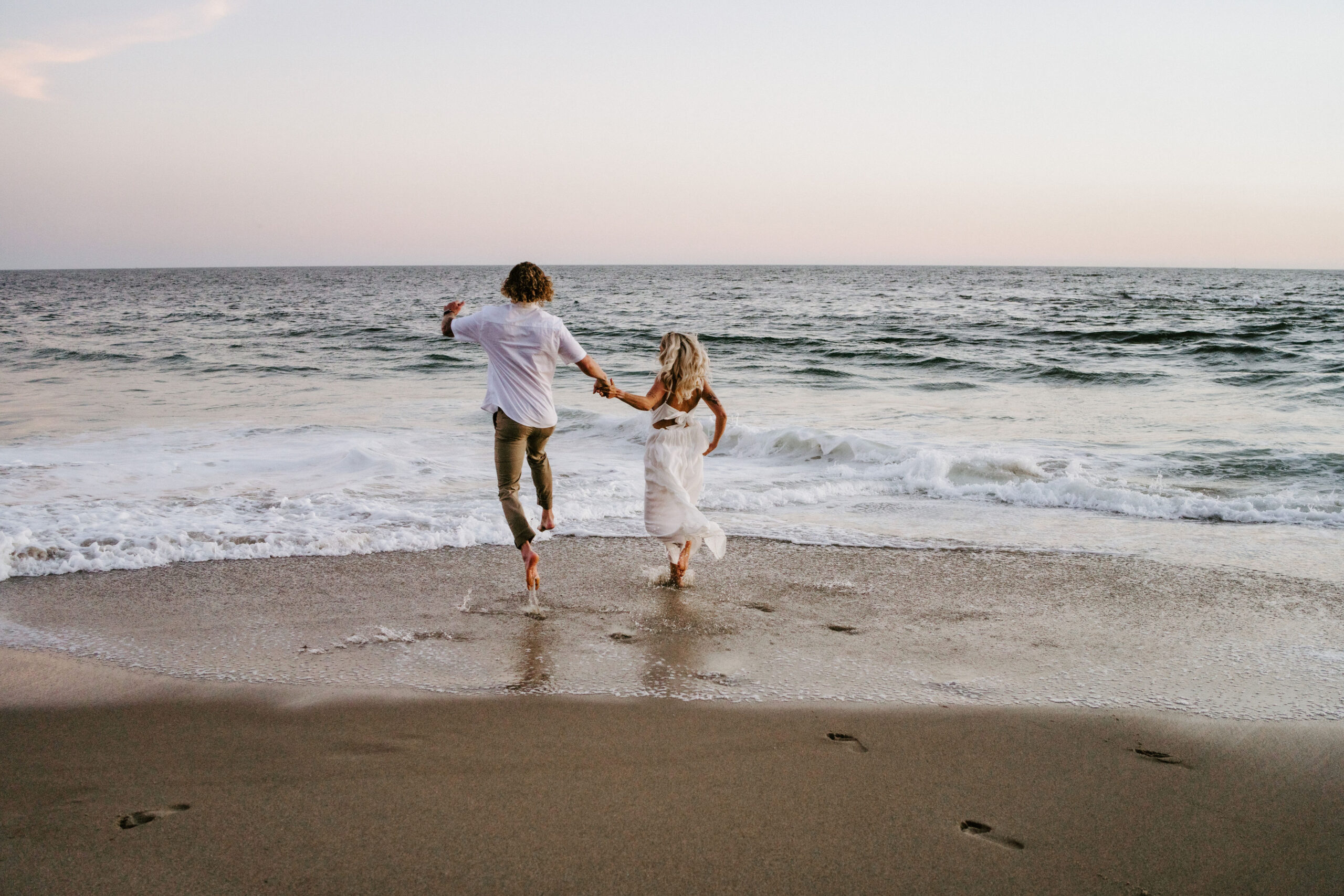 couple eloping and running onto beach at sunset in california