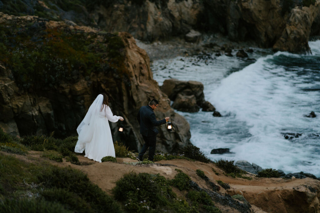 elopement couple hiking with lanterns along Big Sur coast