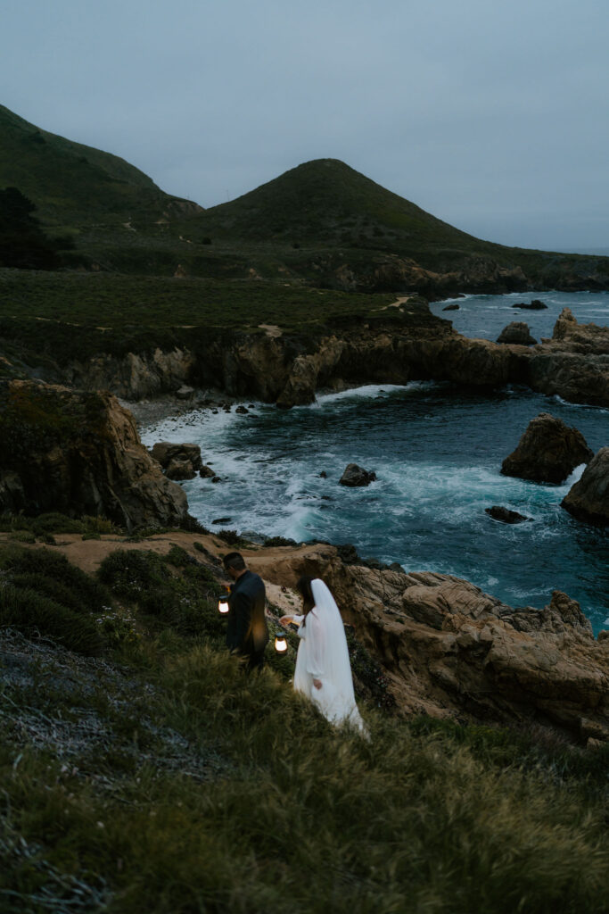 elopement couple hiking with lanterns along Big Sur coast
