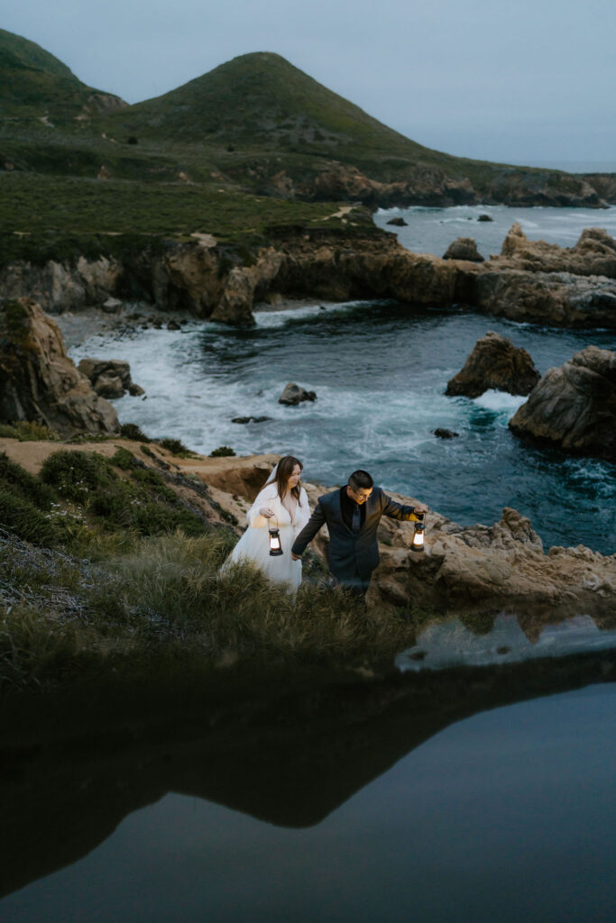 elopement couple hiking with lanterns along Big Sur coast