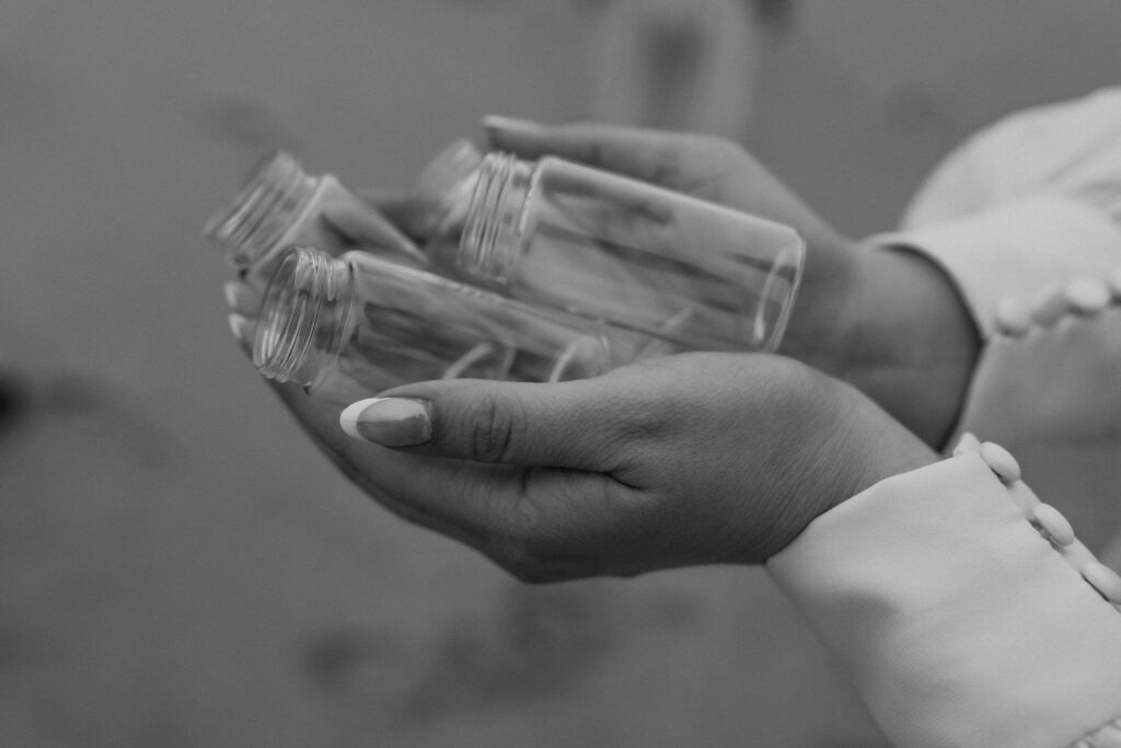 bride holding tiny glass bottles to collect water from the ocean
