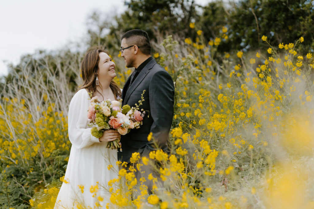 bride and groom posing in a field of wildflowers