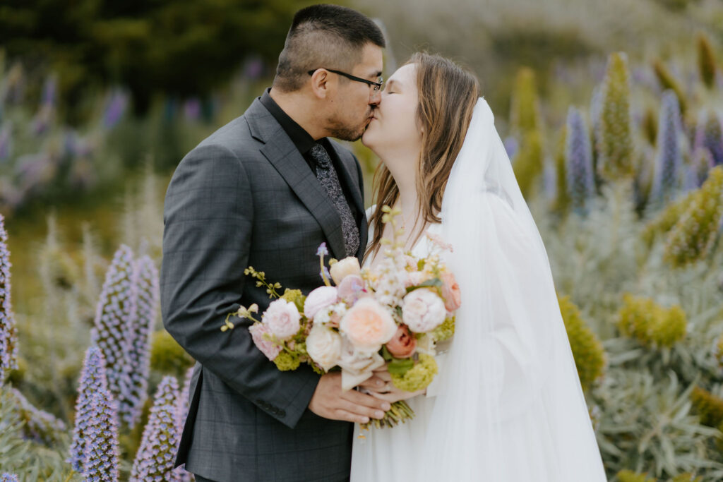 bride and groom posing in a field of wildflowers