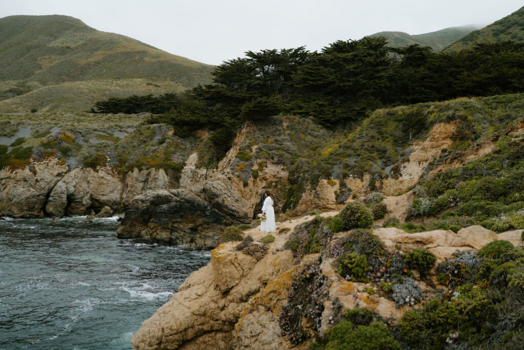 bride and groom on a cliff at Big Sur