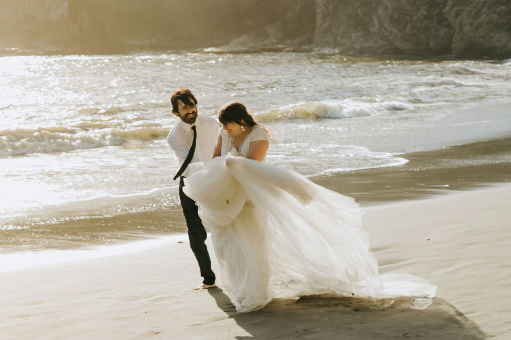 playful bride and groom walking along the shore during their California beach elopement