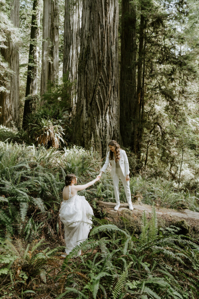 brides hiking through the forest together during their redwoods elopement