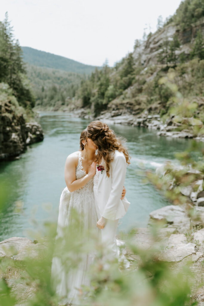 brides posing on a rocky cliff overlooking turquoise smith river