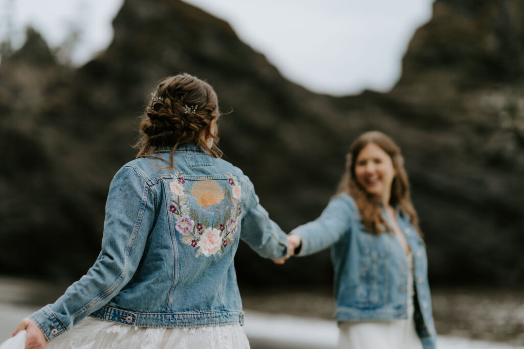 brides walking hand in hand around oregon coast at secret beach