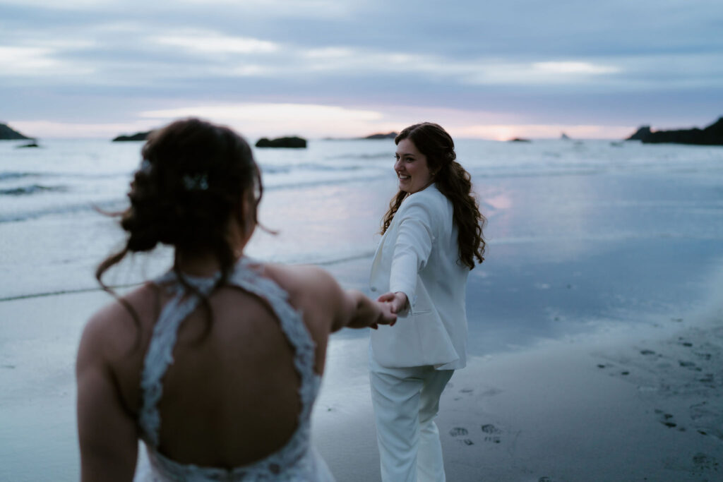 brides walking hand in hand around oregon coast at secret beach