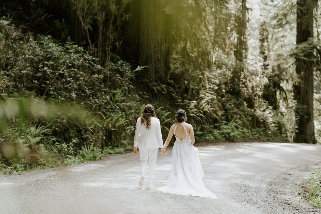 brides walking on a path surrounded by lush trees during their redwoods elopement in Jedediah Smith State Park