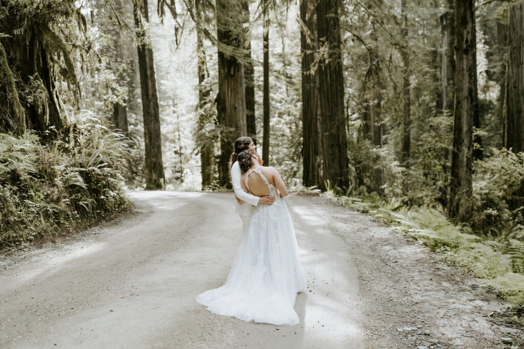 brides walking on a path surrounded by lush trees during their redwoods elopement in Jedediah Smith State Park