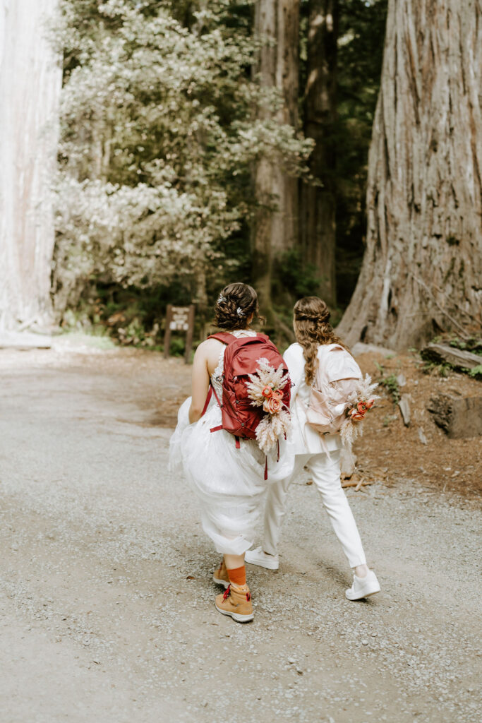 brides hiking surrounded by lush trees during their redwoods elopement in Jedediah Smith State Park