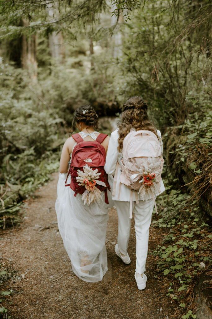 brides hiking through the forest together during their redwoods elopement