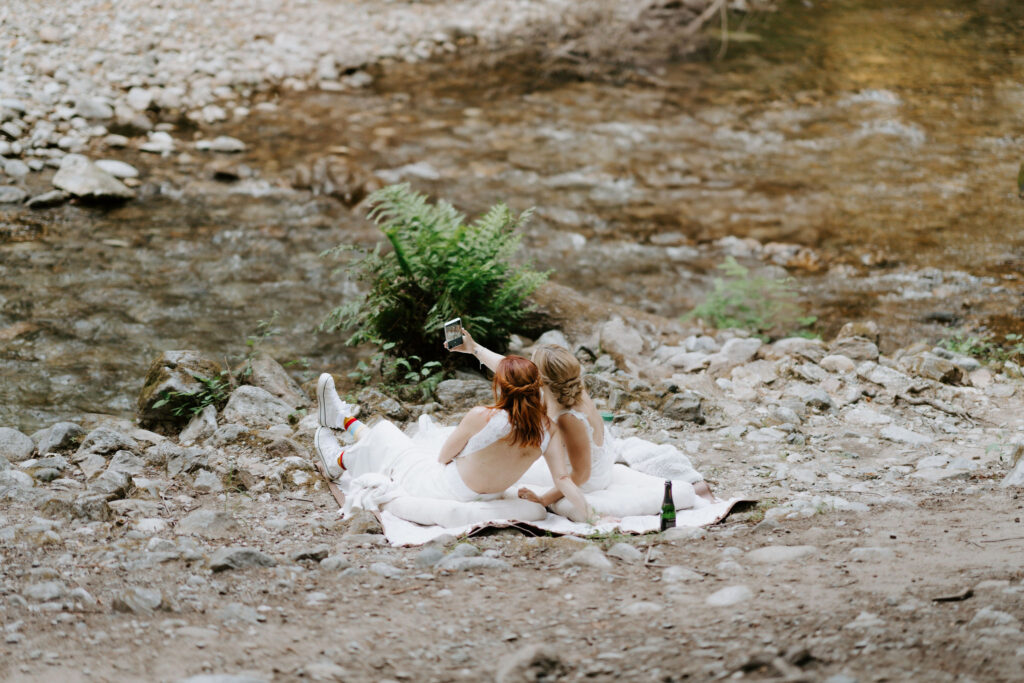 brides settled on a picnic blanket taking a selfie