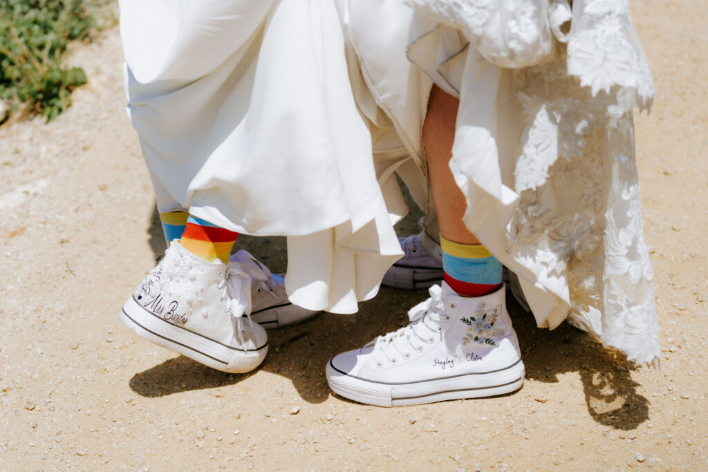brides showing off their rainbow socks and white custom sneakers
