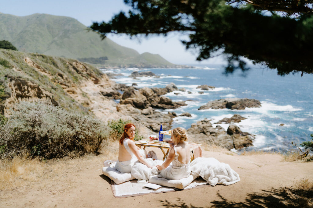 brides enjoying a luxury elopement picnic in big sur overlooking the ocean