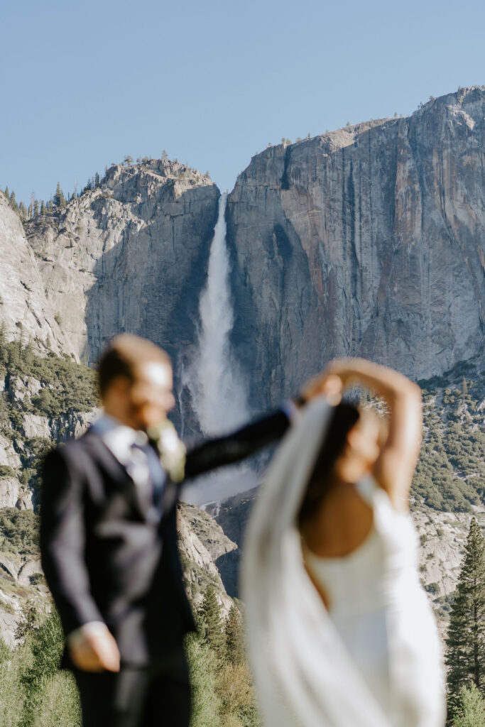 bride and groom in front of a waterfall in yosemite national park
