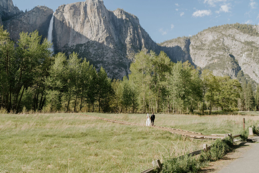 bride and groom walking on a wooden trail in yosemite