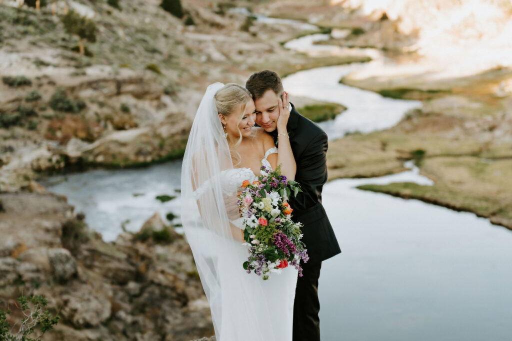 bride and groom next to a winding river with mountain views at mammoth lakes, CA