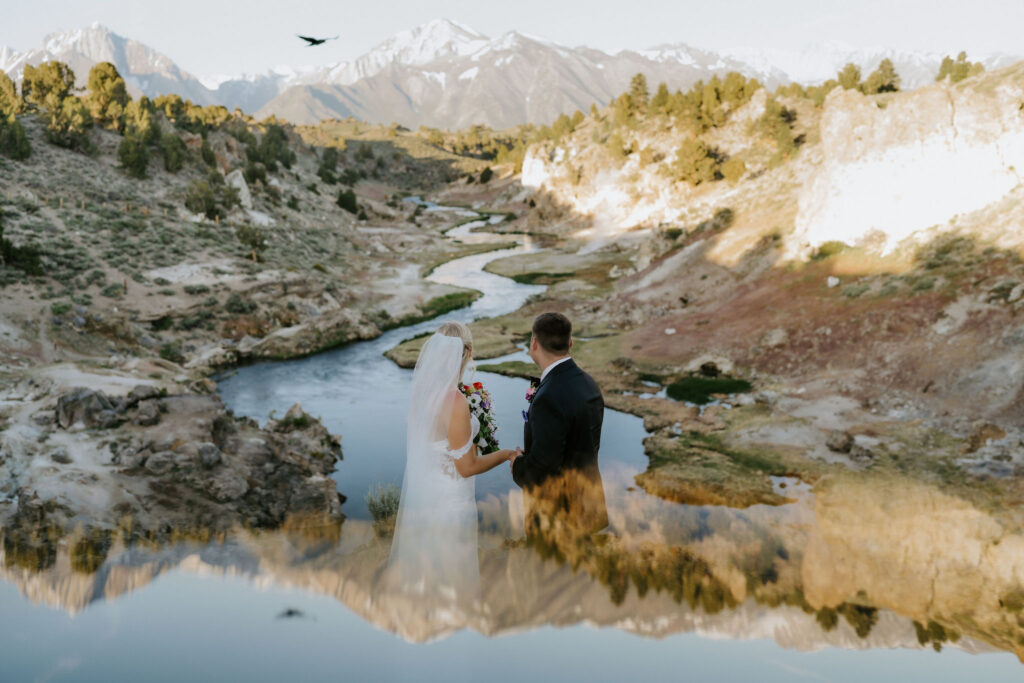 bride and groom next to a winding river with mountain views at mammoth lakes, CA