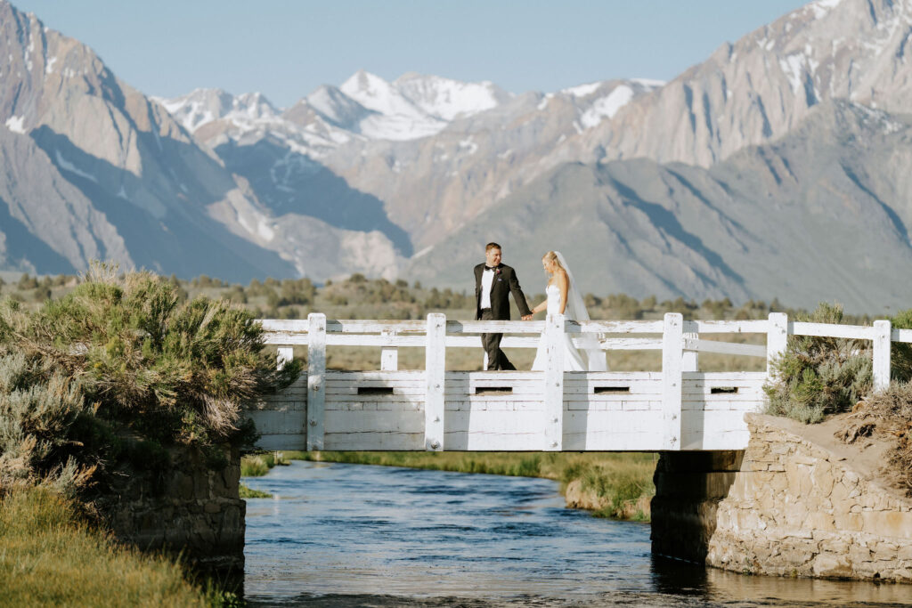 newlyweds walking across a small bridge