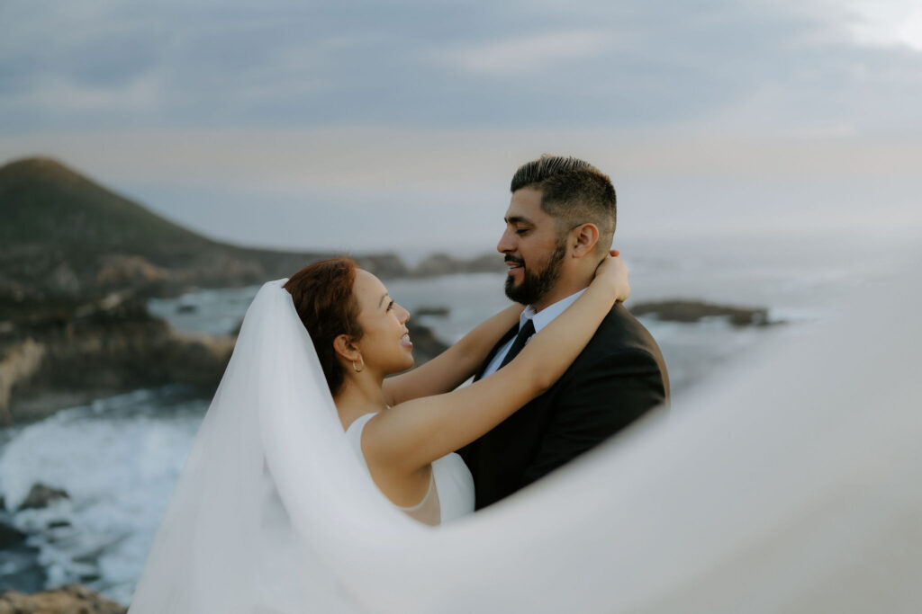 bride and groom posing on the bluffs overlooking the ocean in garrapata state park