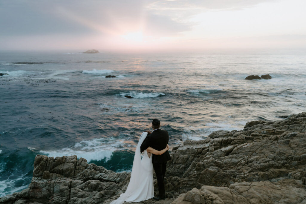 bride and groom posing on the bluffs overlooking the ocean in garrapata state park