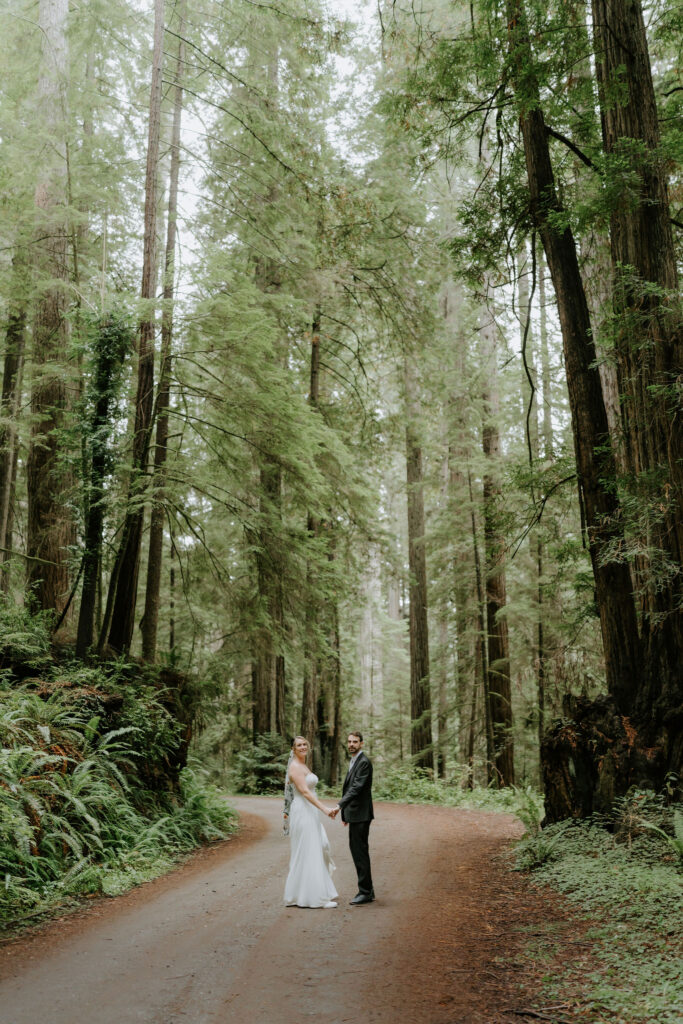 bride and groom hiking through the lush forest during their prairie creek redwoods elopement