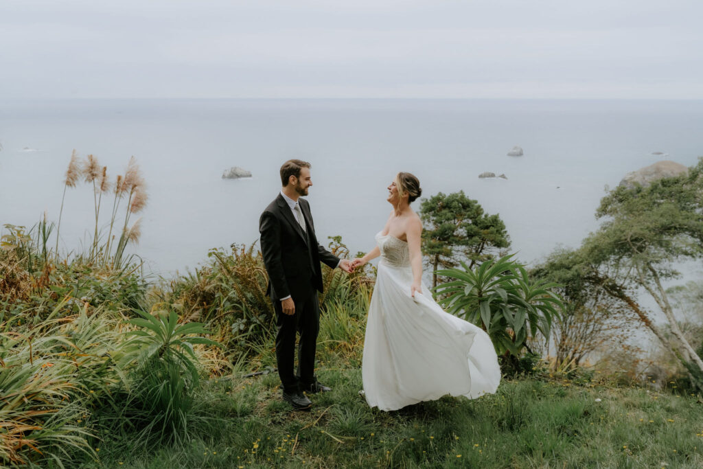 bride and groom holding hands overlooking the ocean during their Trinidad State Beach elopement
