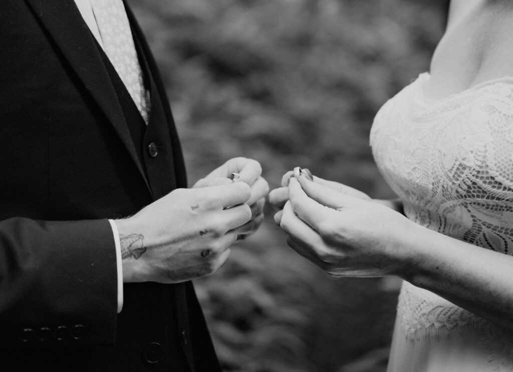 bride and groom exchanging rings surrounded by lush forest during their prairie creek redwoods elopement