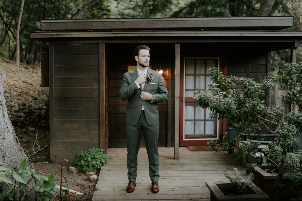 groom getting ready in front of a rustic cabin